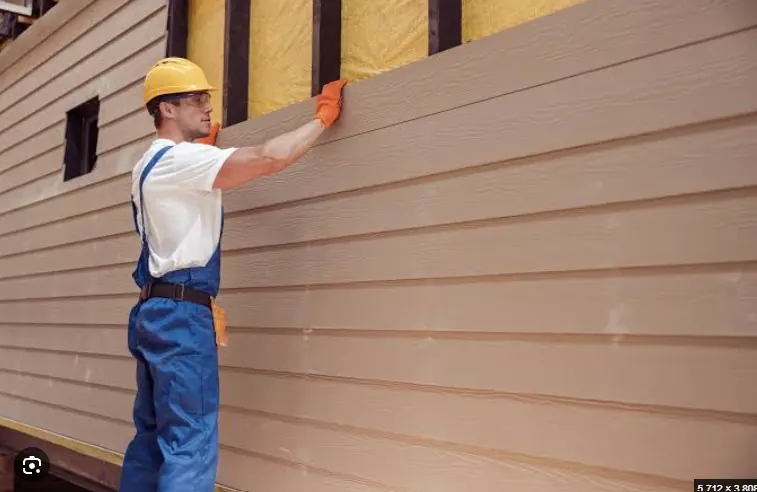Worker positioning a horizontal siding board over exterior insulation